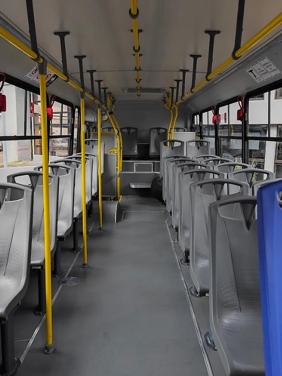 Interior de autobús con asientos altos y cubierta de plástico gris y azul.